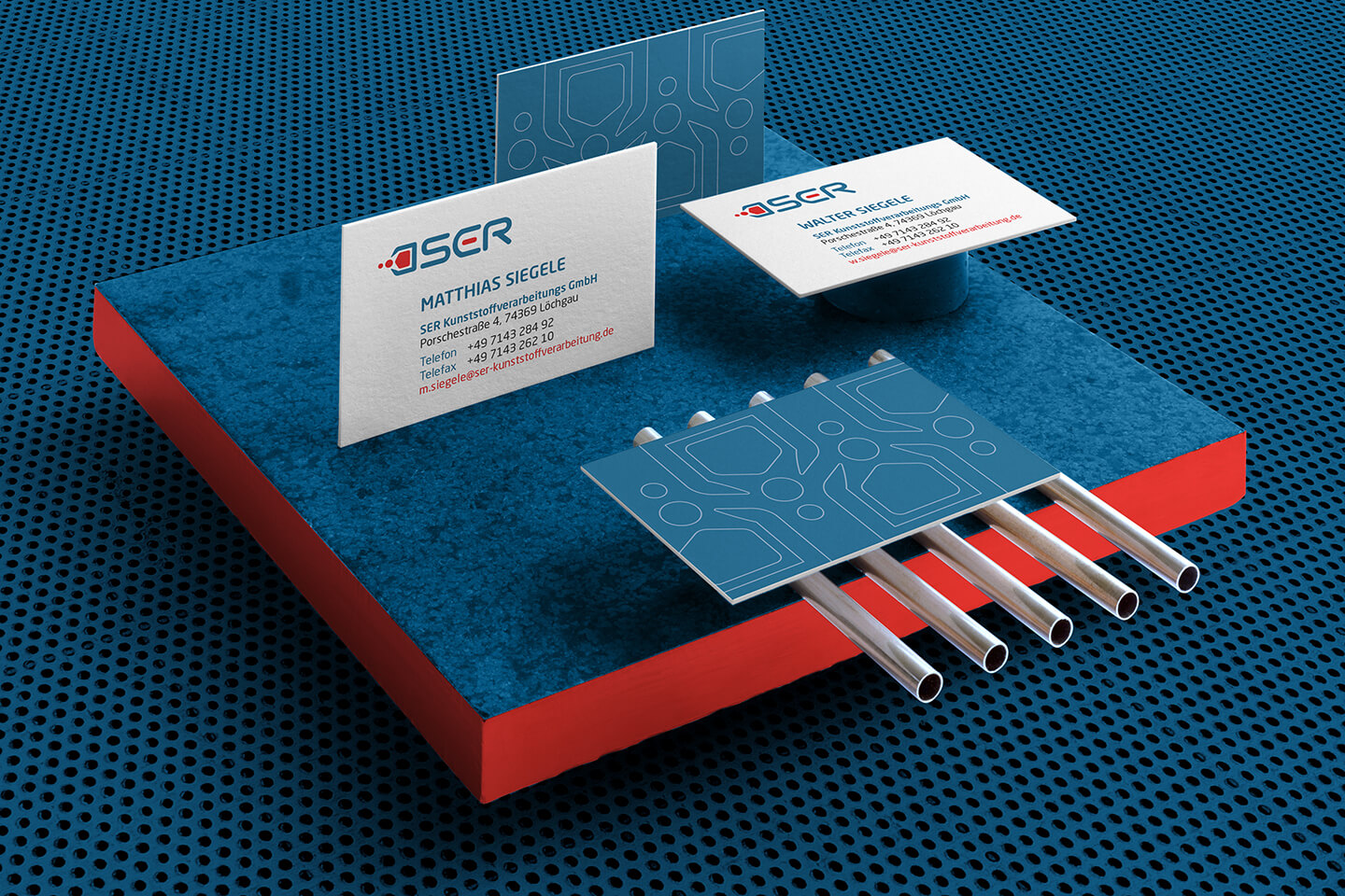 SER Visitenkarten und Markenfarben auf blau-roter industrieller Materialoberfläche.