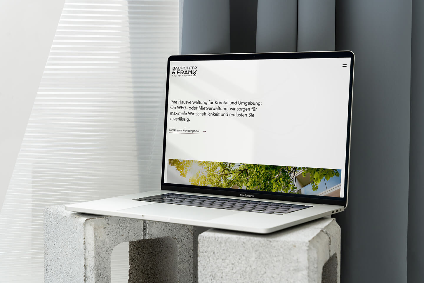 Laptop mit der Website von Bauhoffer & Frank Hausverwaltung auf gestapelten Betonsteinen.