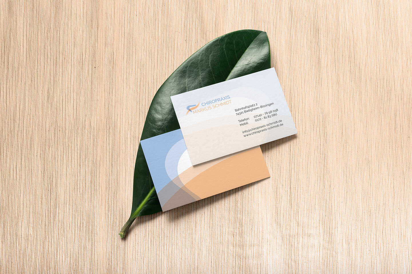 Visitenkarten der Chiropraxis Schmidt auf einem Blatt mit natürlichem Stoffhintergrund.