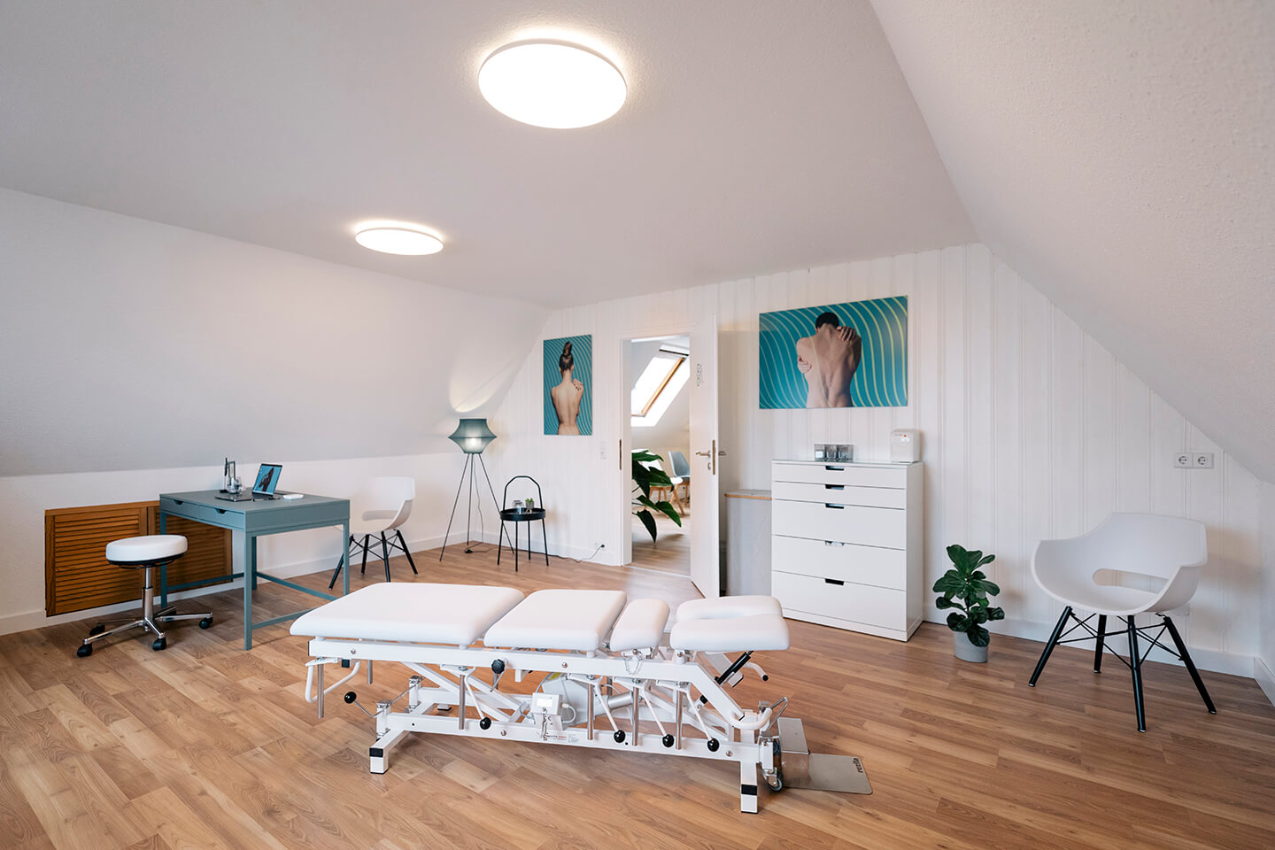Behandlungsraum der Chiropraxis Kevin Holzer mit Therapieliege und gebrandeten Wandbildern.
